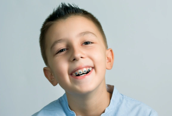 Smiling young boy with braces wearing a light blue shirt