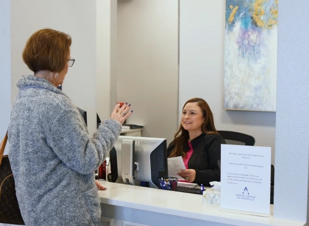 Front desk staff member assisting a patient at the check-in counter of Dental Group of Amarillo